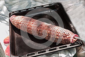 Traditional kokoretsi meat roll on a spindle in a net