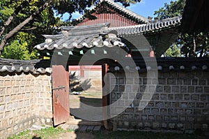 Traditional Korean Hanok Village buildings with old wooden door and big trees in the afternoon in Seoul, South Korea