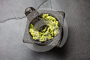 Traditional latin american mexican sauce guacamole in stone mortar, slate gray background