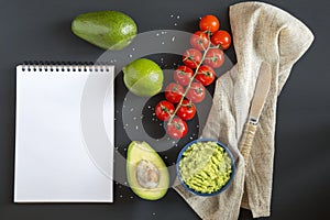 Traditional latinamerican mexican sauce guacamole in ceramic bowl and ingredients on dark background.