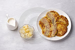 Traditional latkes fritters with sour cream and apple sauce on light gray textured background