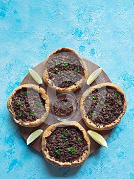 Traditional Lebanese meat pies on a blue table.