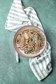 Traditional Lebanese salad tabouli tabule with quinoa, herbs, tomatoes, mint and lemon