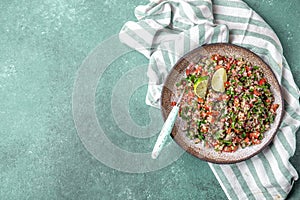 Traditional Lebanese salad tabouli tabule with quinoa, herbs, tomatoes, mint and lemon