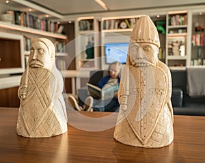 Traditional Lewis Chessmen on table in front of modern library