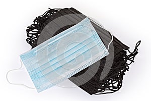 Traditional light blue medical mask on stack black face masks