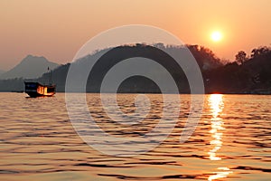 Traditional long boat on the Mekong river with sunset near Luang Prabang Laos