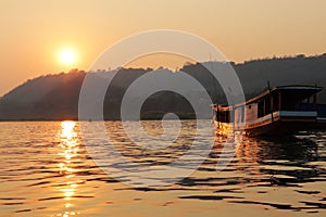 Traditional long boat on the Mekong river with sunset near Luang Prabang Laos