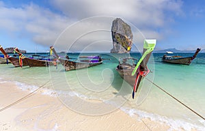 A traditional long tail boat on the beach with poda island background and blue sky