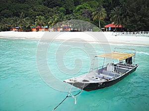 A traditional longtail boat floats in clear water on the island paradise of Pulau Redang, Malaysia.