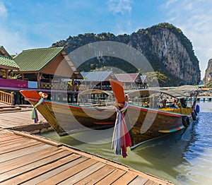 Traditional longtailed speed boats moored on the jetty of the settlement built on stilts of Ko Panyi in Phang Nga Bay, Thailand