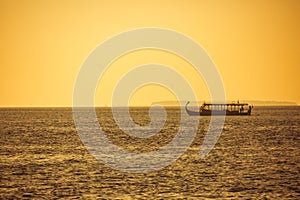 Traditional Maldives boat Dhoni in sunset sea, golden tones and relaxing tropical weather