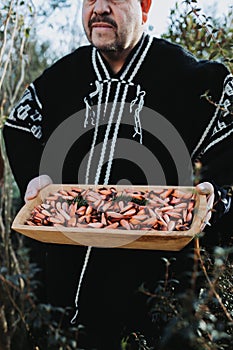 Traditional man using a wool poncho, holding a rustic wooden trough with chilean araucaria pine nuts, pehuen. photo