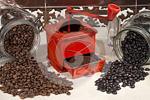 Traditional manual coffee grinder beside different types of coffee beans