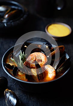Traditional Marseille Bouillabaisse fish soup with prawns, mussels tomato, lobster, squid. Black background.