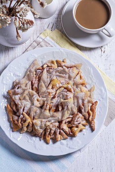 Traditional Maslenitsa dessert angel wings served with coffee on a light background.