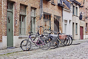 Traditional medieval town. Narrow paved street with old brick houses and bikes near entrance