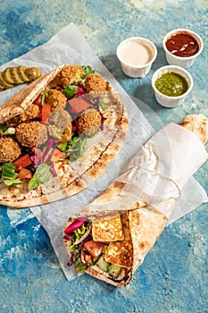 Traditional Mediterranean Arabic grilled halloumi and falafel, hummus and vegetables in flatbread wraps with herbs and sauces