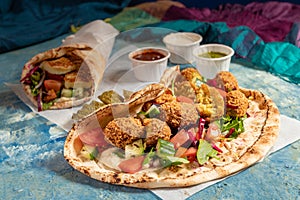 Traditional Mediterranean Arabic grilled halloumi and falafel, hummus and vegetables in flatbread wraps with herbs and sauces