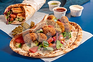Traditional Mediterranean Arabic grilled halloumi and falafel, hummus and vegetables in flatbread wraps with herbs and sauces