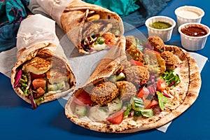 Traditional Mediterranean Arabic grilled halloumi and falafel, hummus and vegetables in flatbread wraps with herbs and sauces