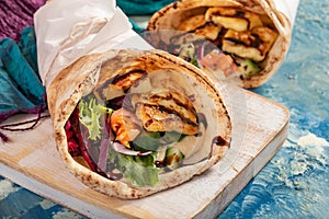 Traditional Mediterranean Arabic grilled halloumi, hummus and vegetables in flatbread wraps topped with herbs and balsamic vinegar