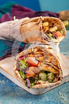 Traditional Mediterranean Arabic grilled halloumi, hummus and vegetables in flatbread wraps topped with herbs and balsamic vinegar