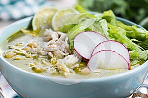 Traditional mexican green pozole soup on wooden table photo