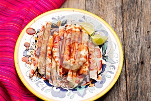 Mexican jicama  cutted with chili powder and piquant sauce on wooden background