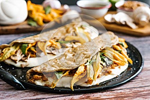 Traditional mexican quesadillas with squash blossom, melted oaxaca cheese, pork rind chicharrÃ³n and mushrooms in Mexico City