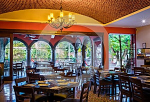 Traditional mexican restaurant interior with chairs and tables, chandelier and brick ceiling