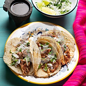 Mexican slow cooked lamb tacos also called barbacoa on turquoise background photo