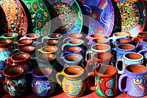 Traditional Mexican souvenirs. Multi-colored ceramic mugs and tableware in the gift shop. Selective focus.