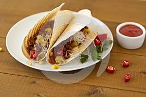 Traditional mexican tacos with meat and vegetables, spicy tomato sauce and cheese on a plate.
