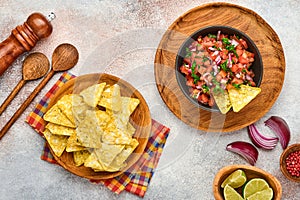 Traditional Mexican tomato sauce salsa with nachos and ingredients tomatoes, chile, garlic, onion on light slate stone background