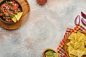 Traditional Mexican tomato sauce salsa with nachos and ingredients tomatoes, chile, garlic, onion on light slate stone background. photo