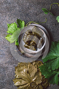 Traditional Middle Eastern dolma or tolma. Grape leaves stuffed with meat and rice. On Gray plate, gray concrete