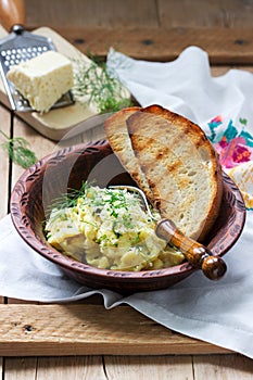 Traditional Moldavian or Romanian dish omelet with cheese, served with bread on a wooden surface. Rustic style.