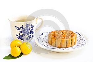 Traditional mooncake with tea and small three oranges on leaves