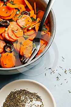 Traditional Moroccan cooked carrot salad North African vegan dish with chopped parsley and olives on gray plate close-up