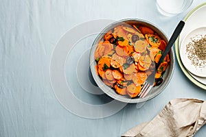 Traditional Moroccan cooked carrot salad North African vegan dish with chopped parsley and olives on gray plate top view