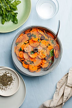 Traditional Moroccan cooked carrot salad North African vegan dish with chopped parsley and olives on gray plate top view