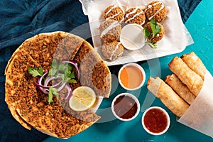 Traditional Moroccan pizza flatbread topped with red lentils, falafel and cheese rolls served with dips