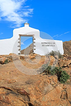 Traditional municipality sign white arch gate near Betancuria village with desert landscape in the background, Fuerteventura,
