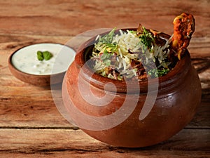 Traditional Murgh dum Biryani made of Basmati rice cooked with masala spices, served with yogurt on traditional clay pot,