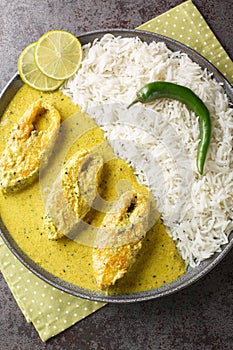 Traditional Mustard Fish Curry Shorshe Ilish or Hilsa closeup on the plate on the table. Vertical top view