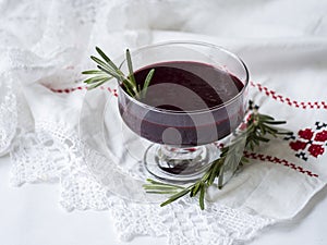 Traditional national belarussian dessert, kulaga, kisel from frozen black currants with rosemary on a white table in