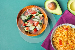 Traditional National Mexican Tomato Rice Stewed Pilaf with Hot Chili Peppers Garlic in Bowl. Fresh Cucumber Onion Salsa Avocado