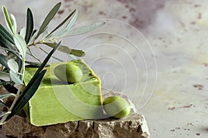 Traditional natural organic olive soap. Close up of handmade soap bar with green olives and leaves on rustic background. Body care