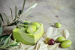 Traditional natural organic olive soap. Handmade soap bar with green olives and leaves on the tissue on rustic background. Body